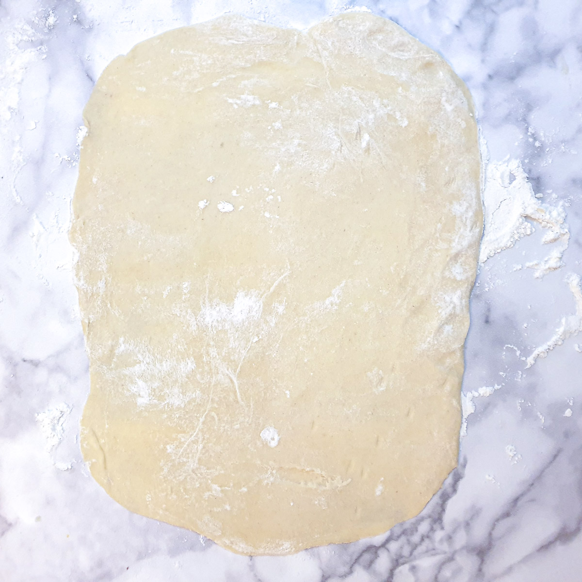 A rectangle of rolled pastry on a table.