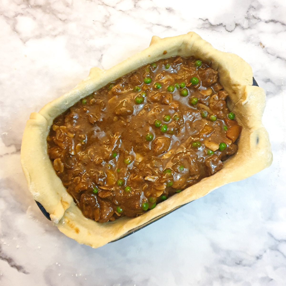 Lamb filling in a pastry-lined baking dish.