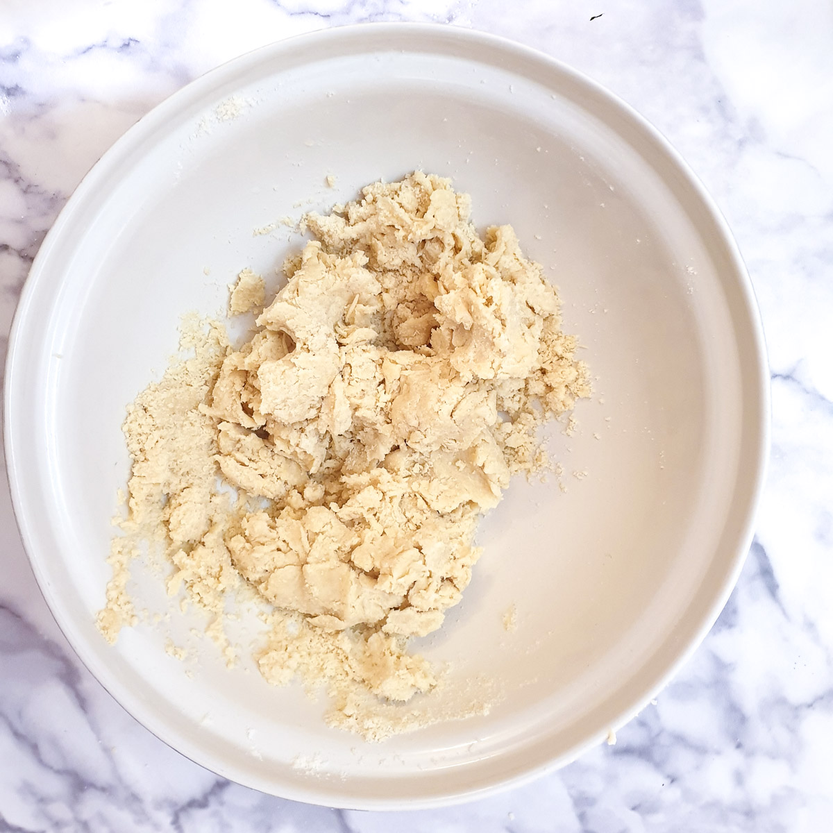 A ball of shaggy dough in a mixing bowl.