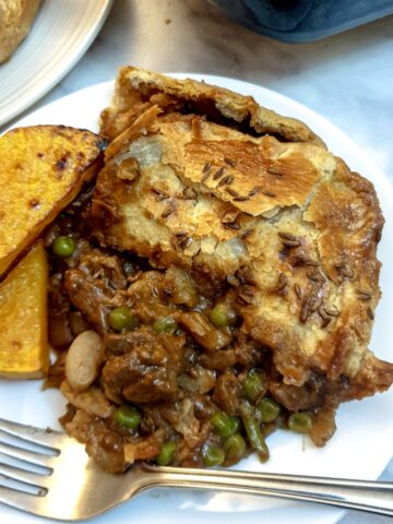 A slice of Moroccan lamb pie on a white plate with two slices of roasted butternut squash.