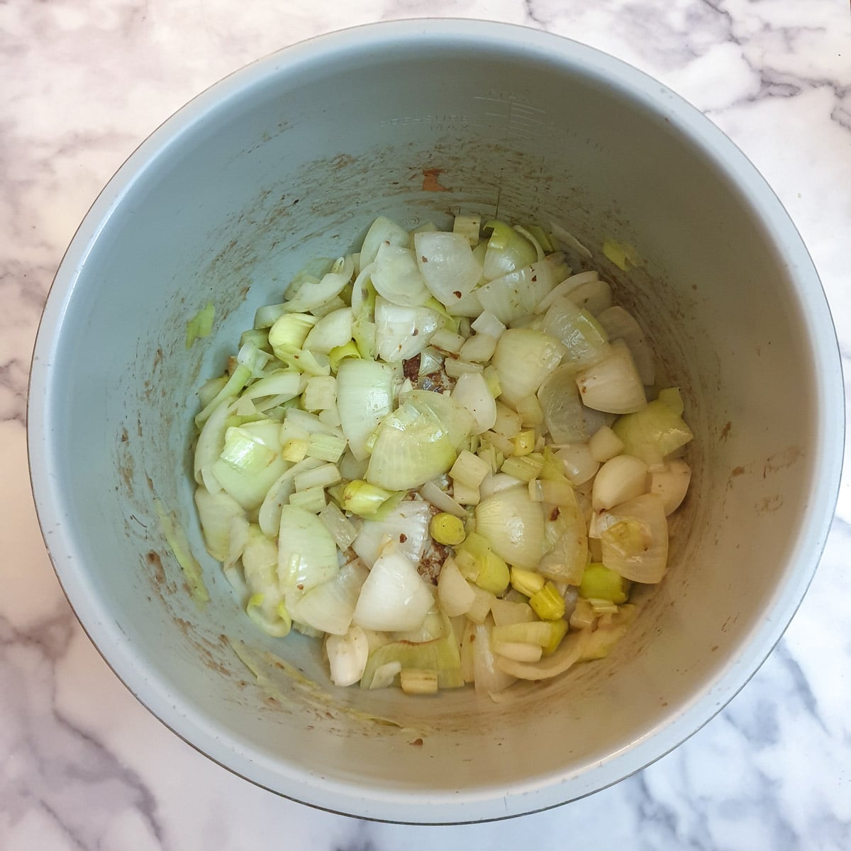 Onions and celery being sauteed in a pressure cooker.