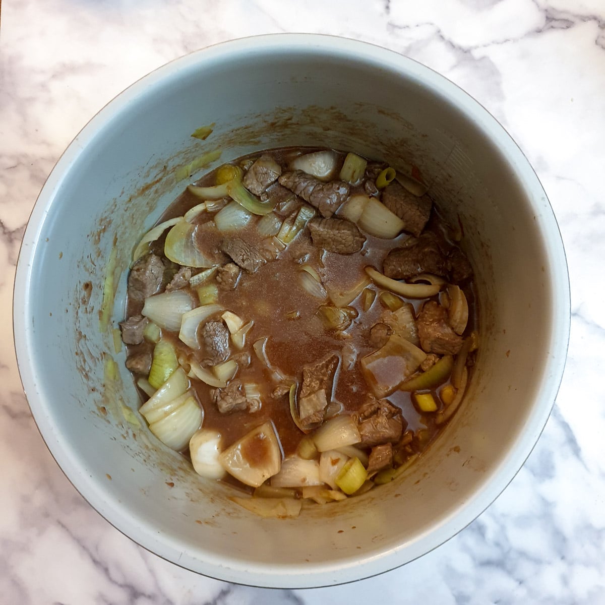 Beef cubes, onions and gravy in a pressure cooker.