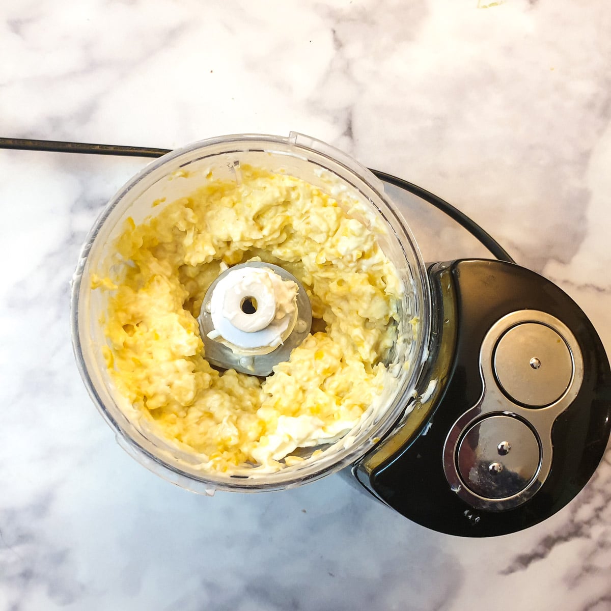 Sweetcorn kernels and cream cheese after being blended in a small food processor.