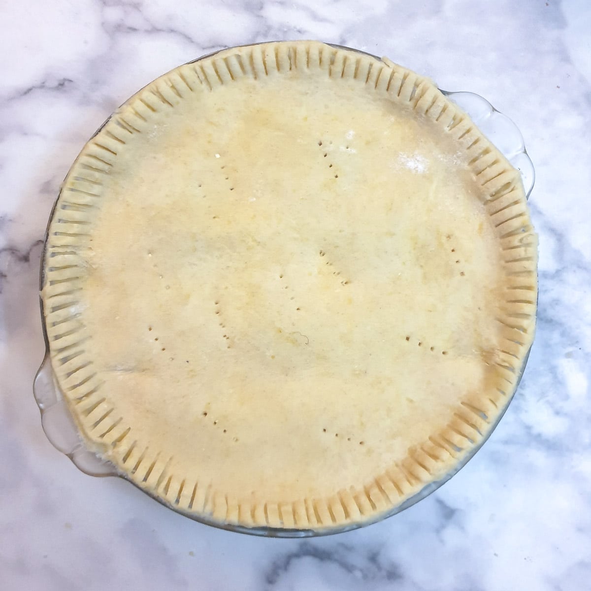 Unbaked bacon and egg pie, crimped and trimmed ready for the oven.