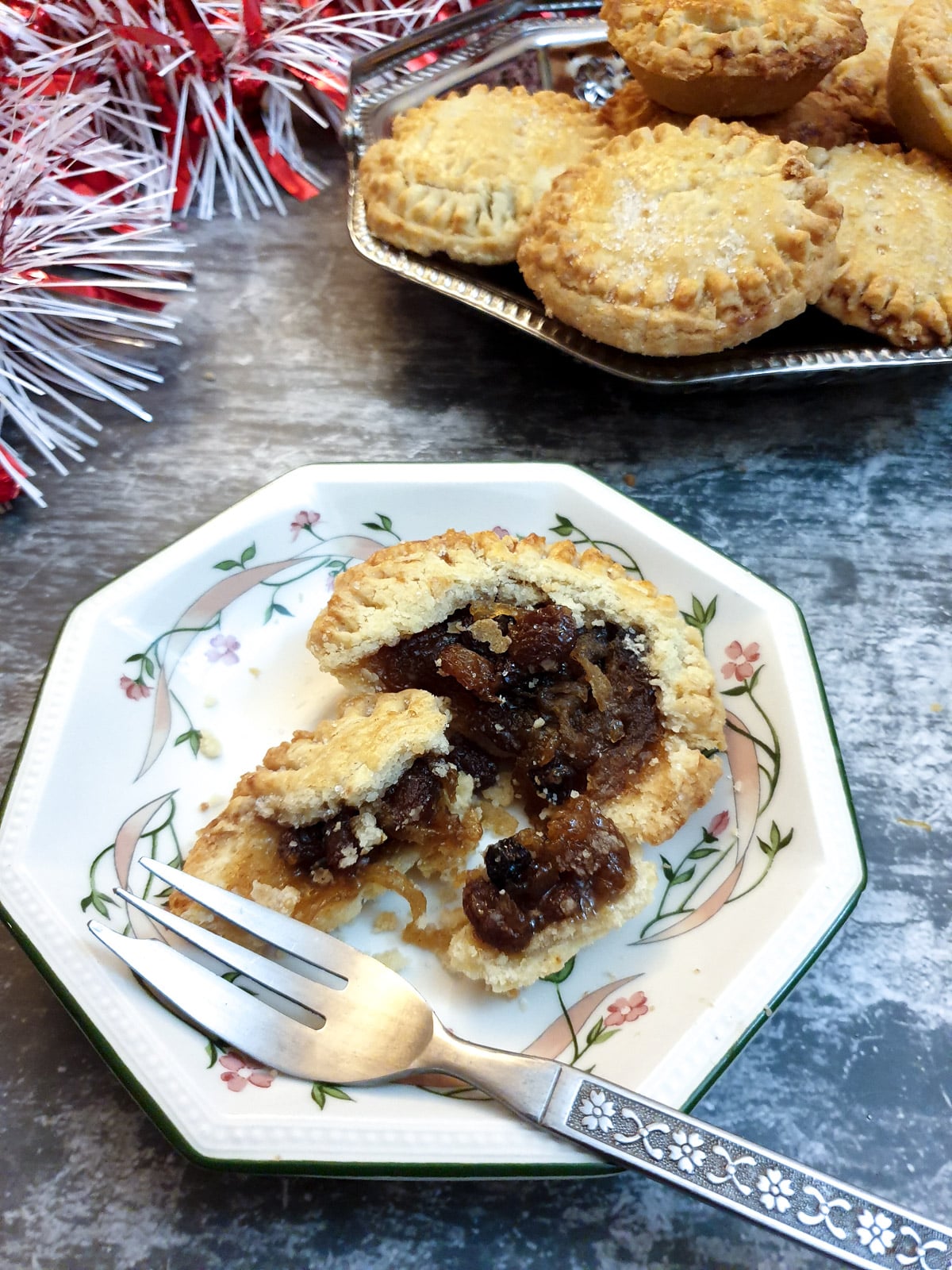 Close up of a cut-open mince pie on a plate with a cake fork.