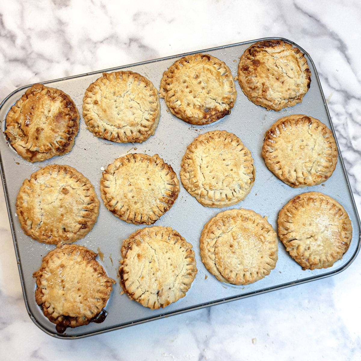 12 baked Christmas mince pies in a jam-tart tin.