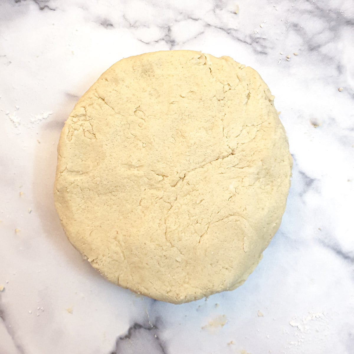 A flattened disk of pastry on a work surface.