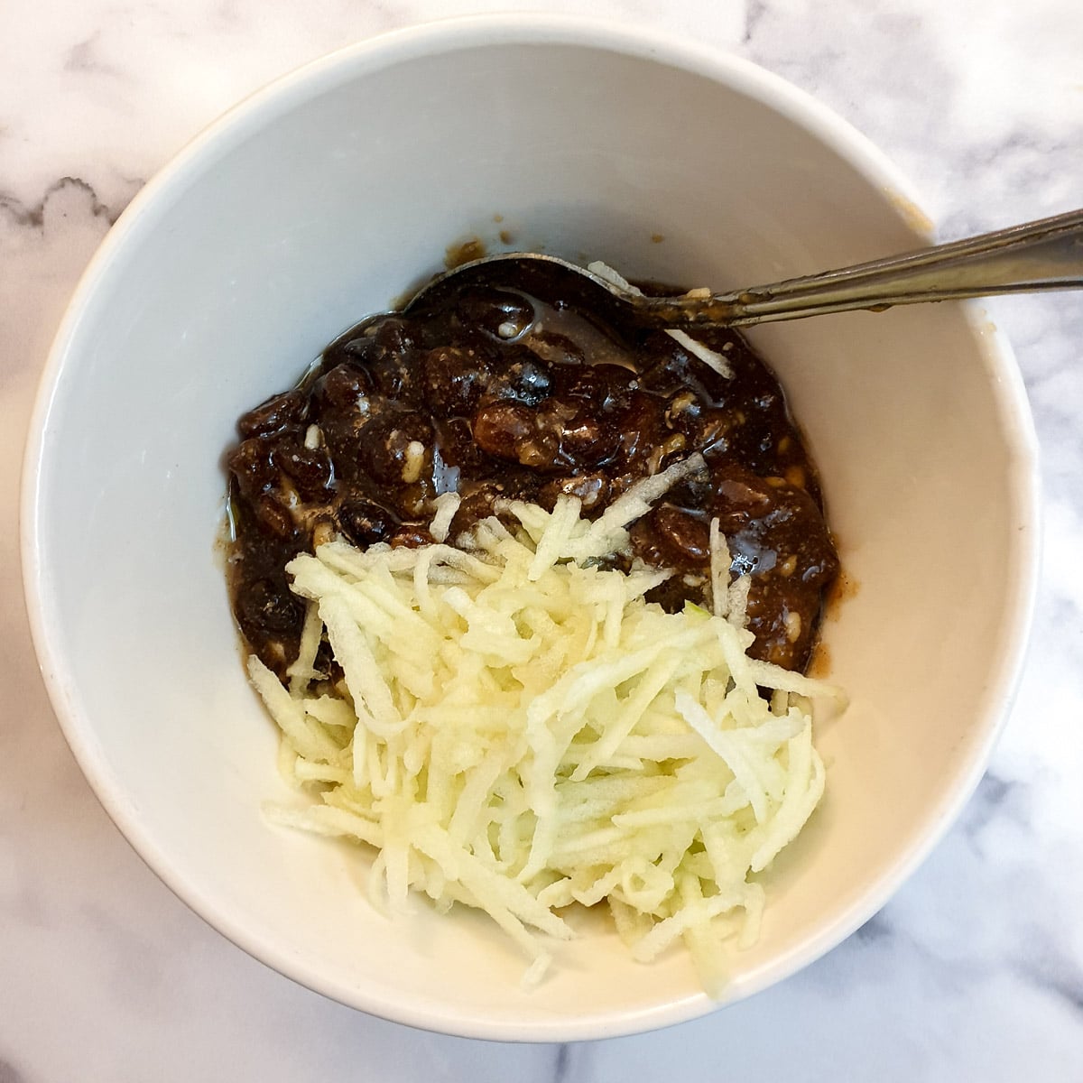 Mince meat and grated apple in a small mixing bowl.