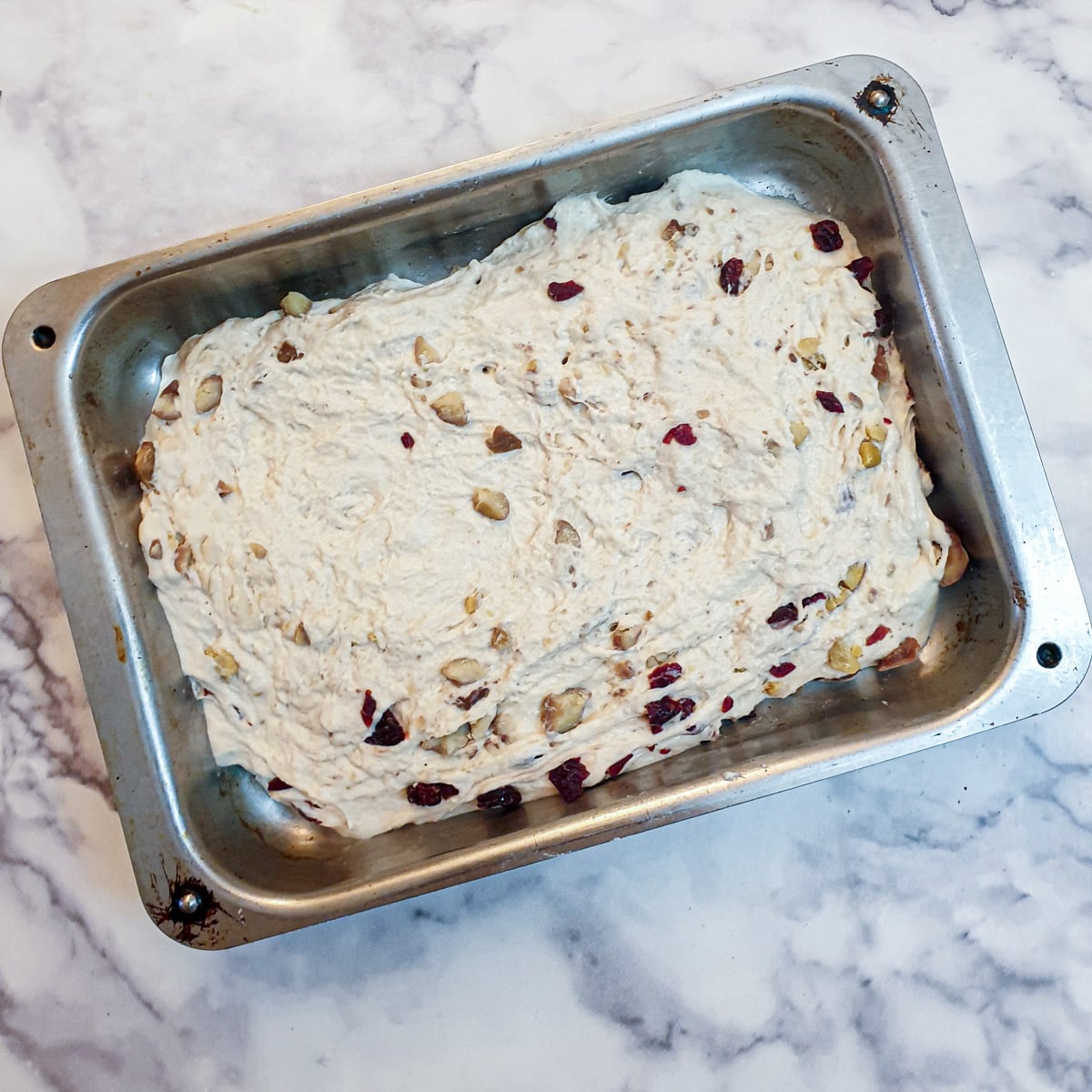 A metal baking dish containing unrisen focaccia dough.