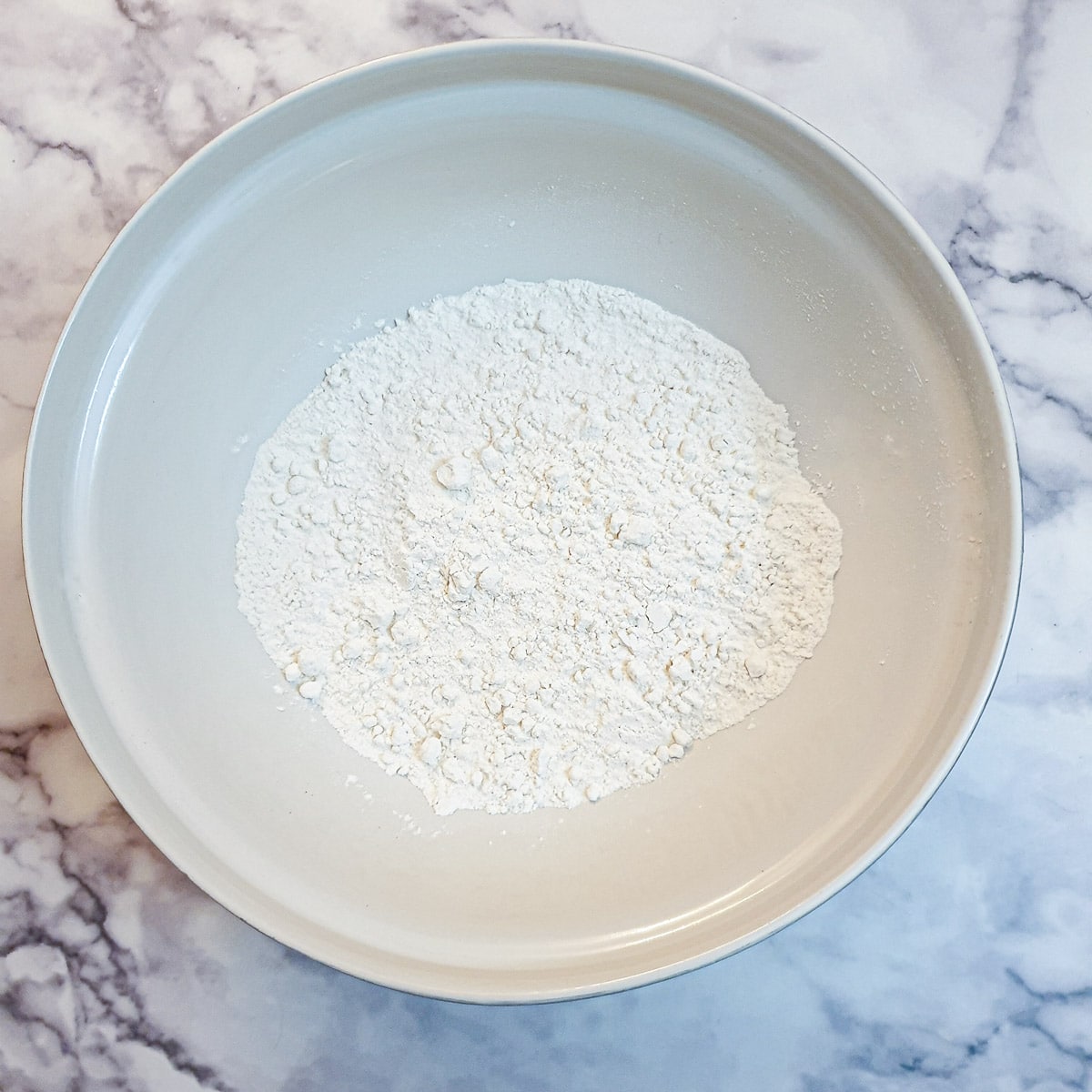 Flour in a large white mixing bowl.