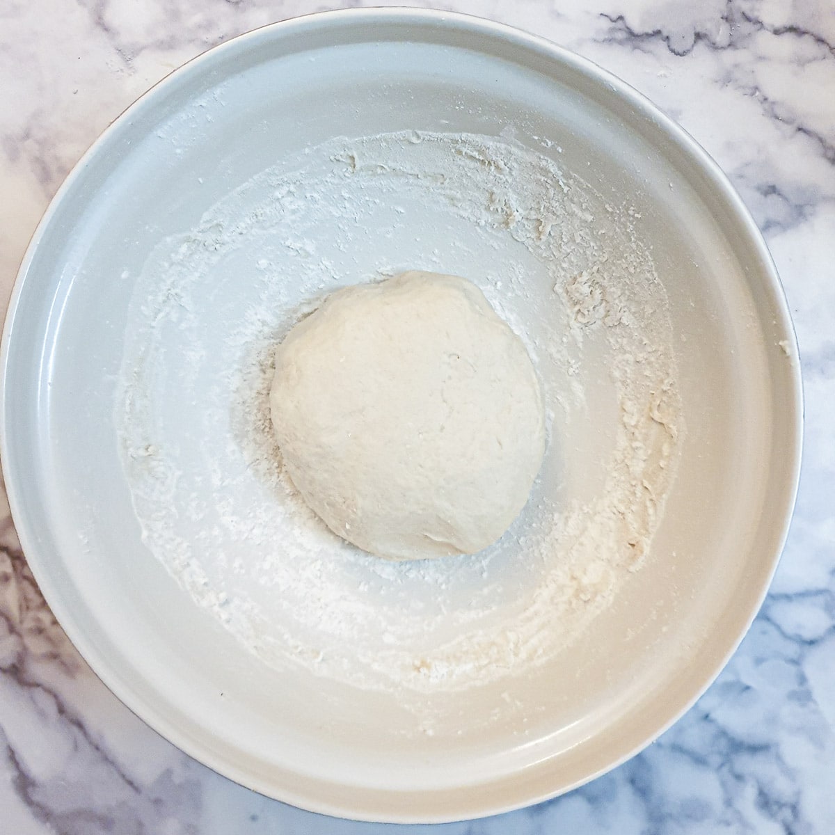 A ball of kneaded dough in a mixing bowl.