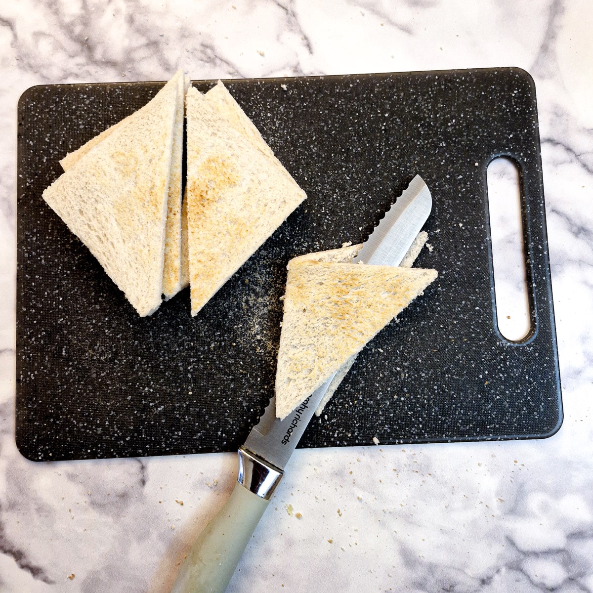Slice of toast cut into triangles with one piece being cut through the middle to form 2 thinner triangles.