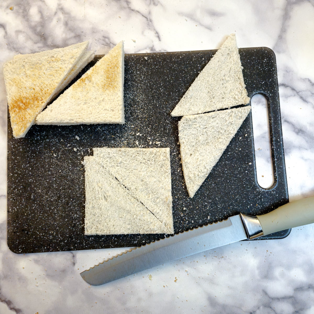 Thinly sliced unbaked melba toast triangles on a chopping board.