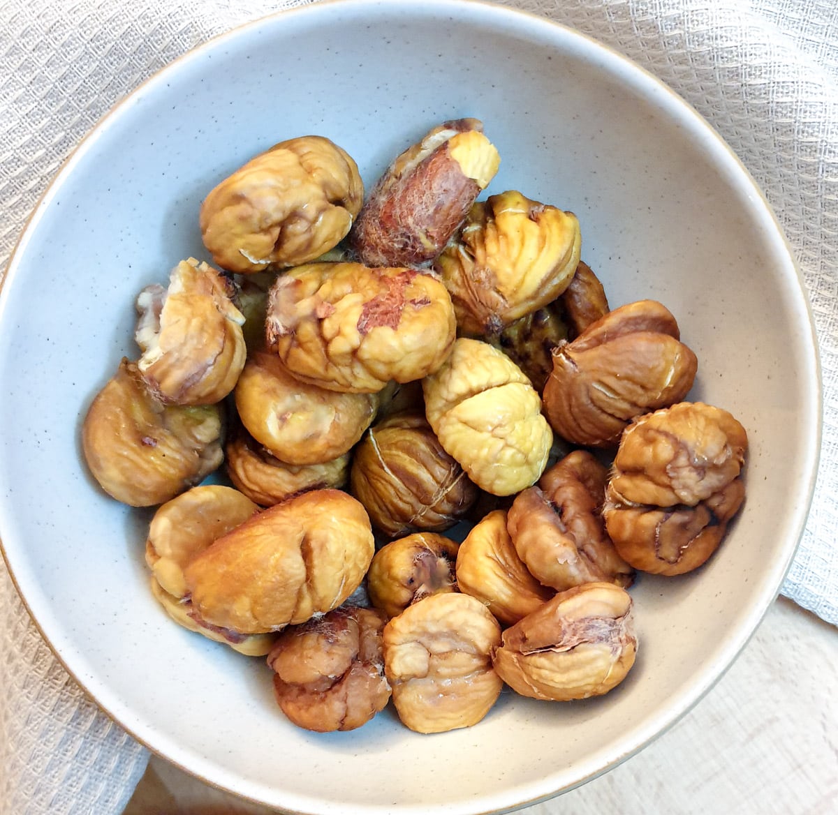 A small white dish of peeled roast chestnuts.