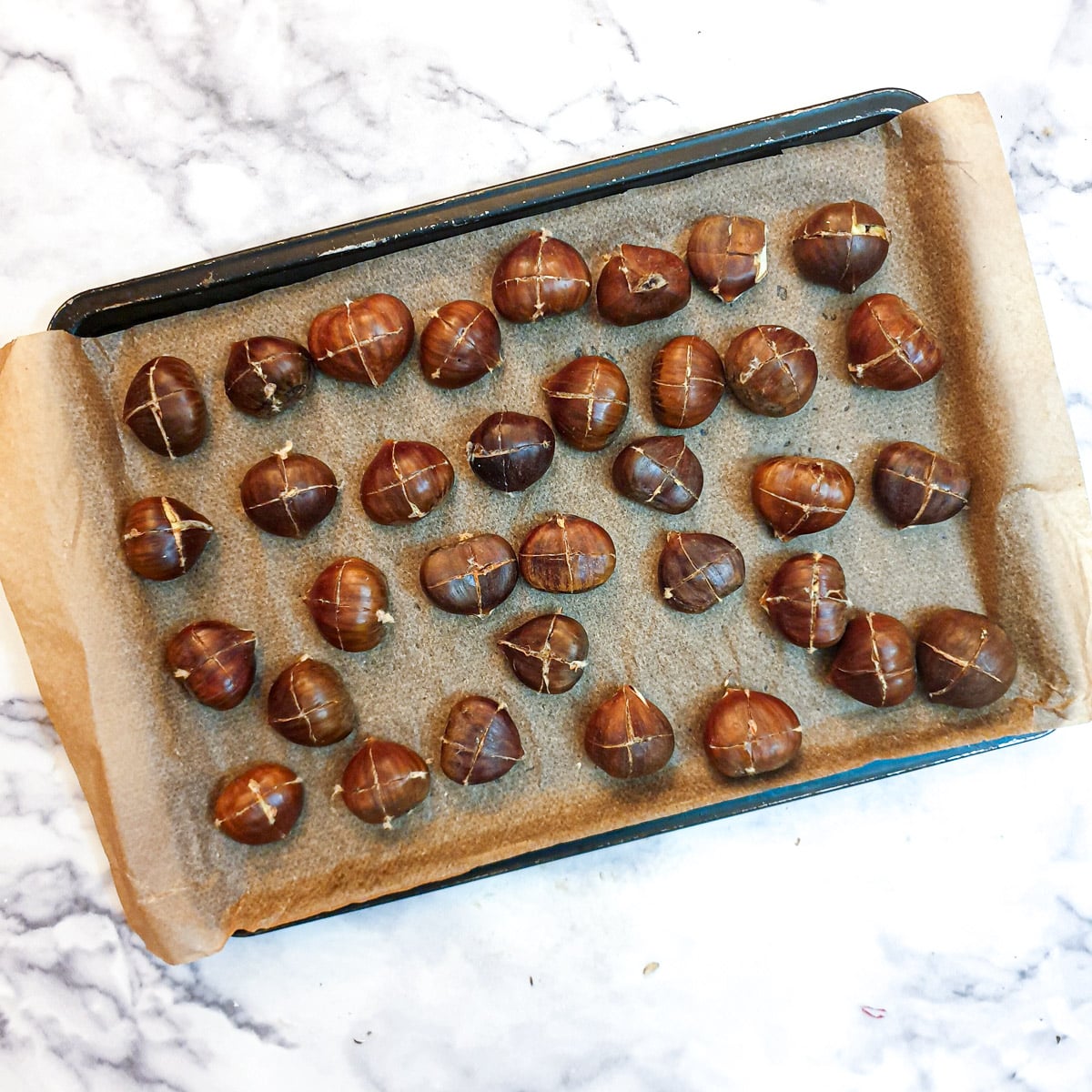 Prepared chestnuts on a baking tray.