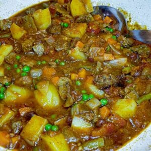 A close-up of a dish of leftover lamb curry, showing the meat and vegetables in the thick gravy.