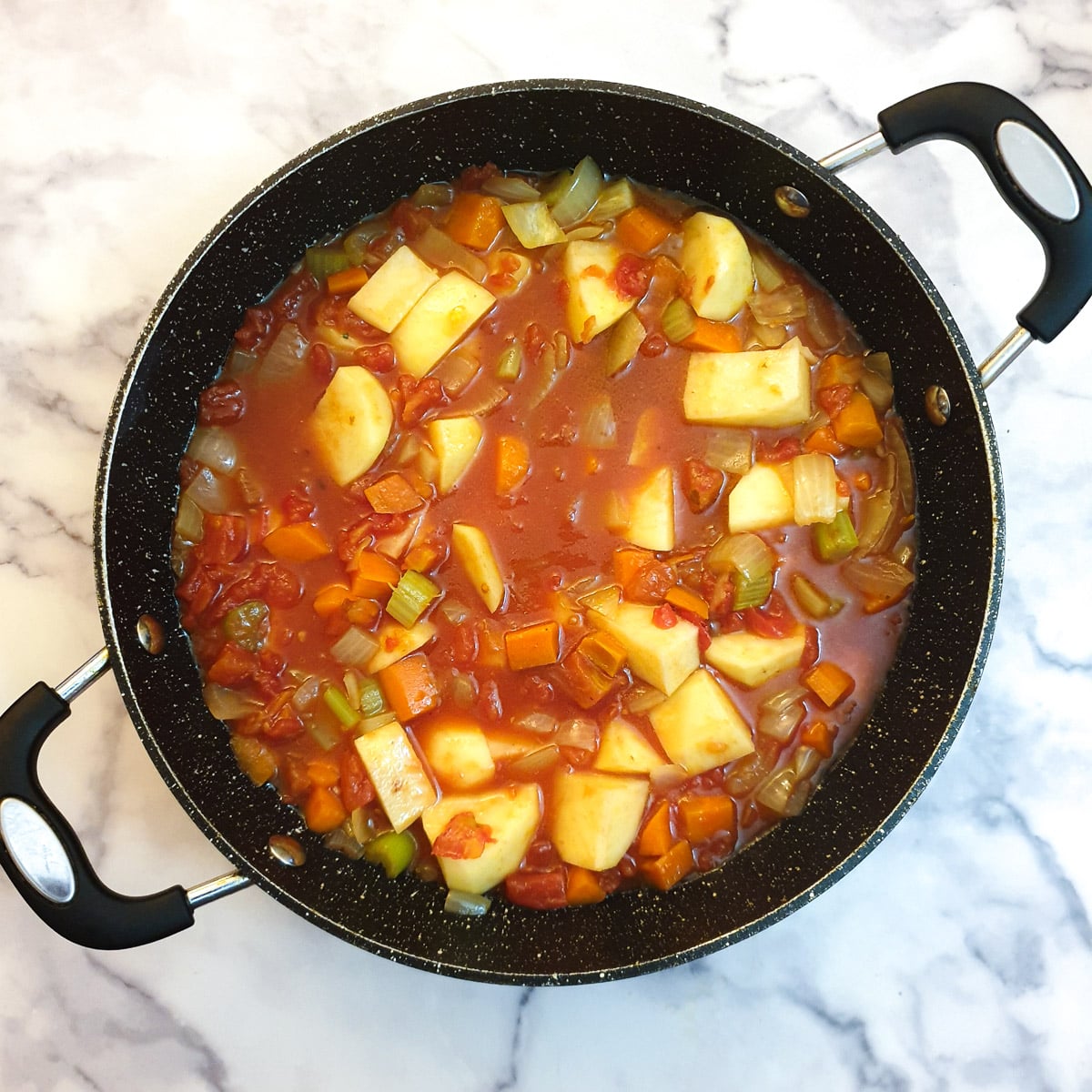 Raw potatoes, stock and tinned tomatoes added to the lamb curry.