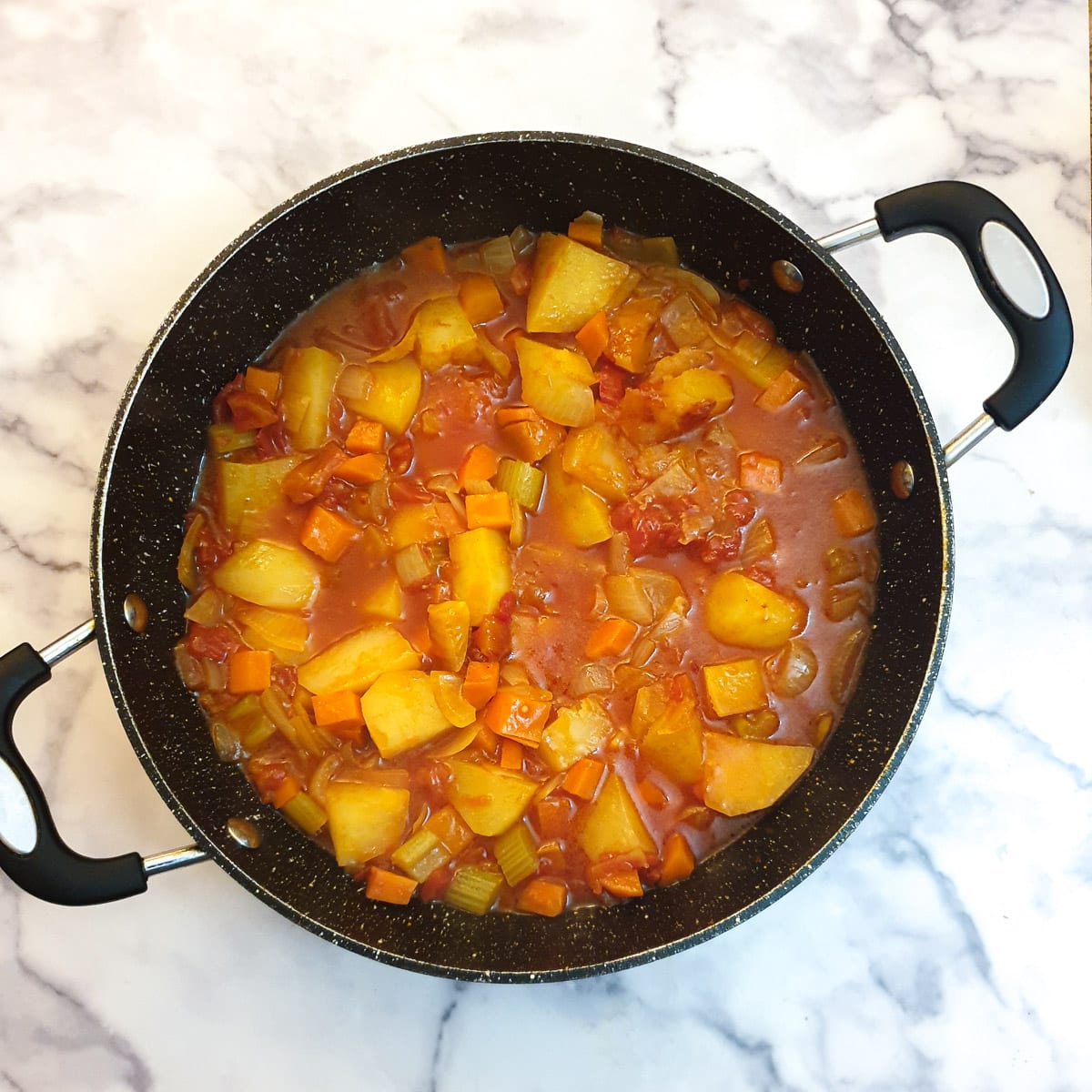 Cooked potatoes and tomatoes with curry sauce ready for the lamb to be added.