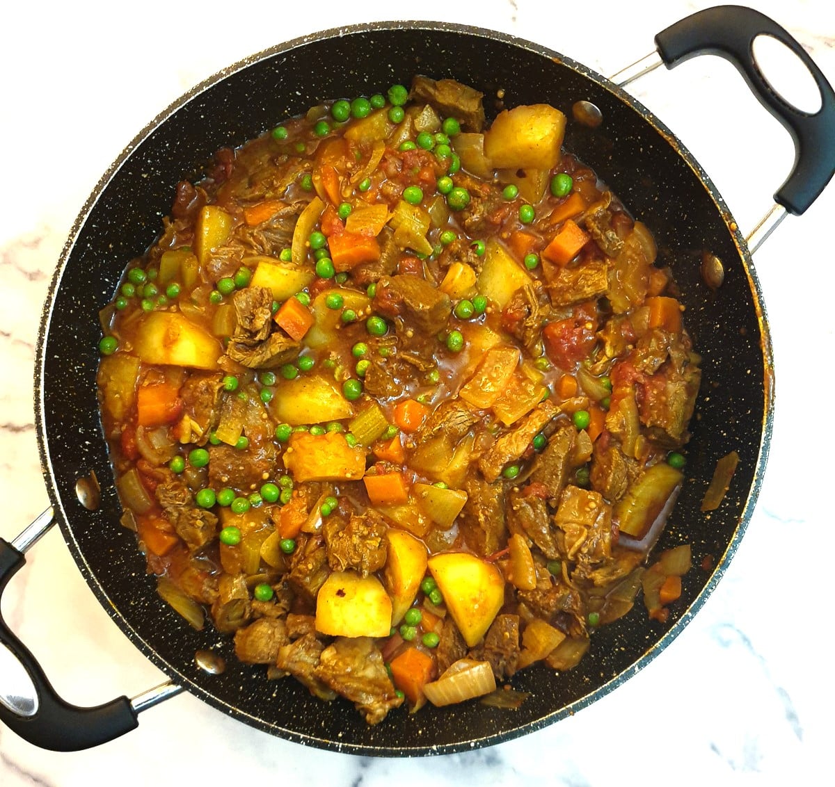 A finished dish of leftover lamb curry with the addition of frozen peas.