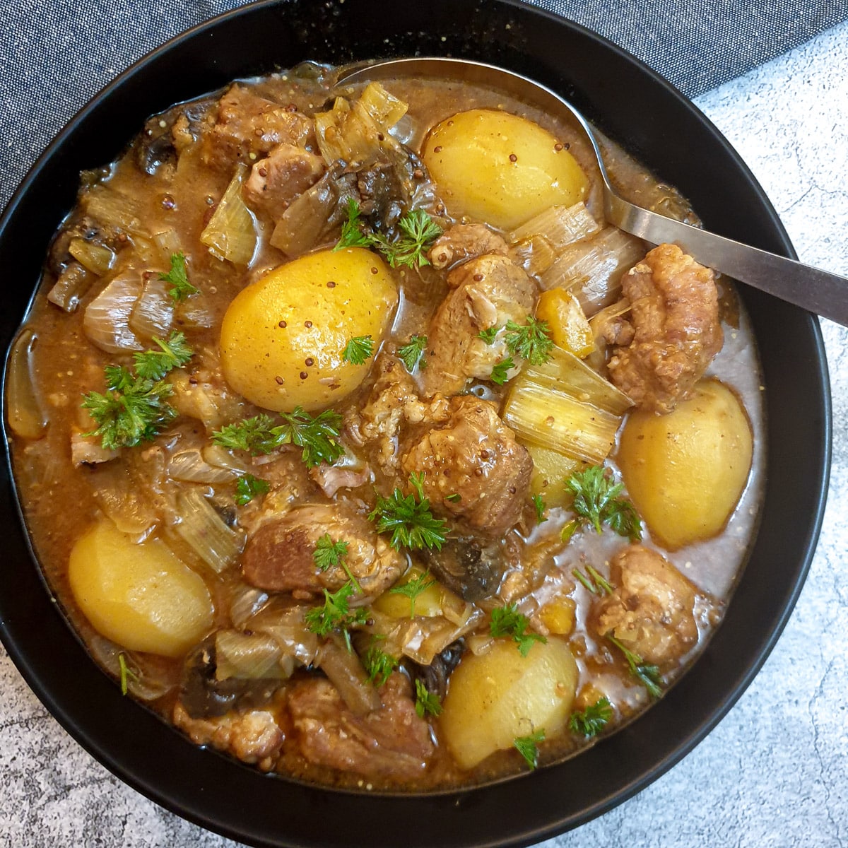 Overhead shot of a black serving dish of pork casserole with honey and mustard.