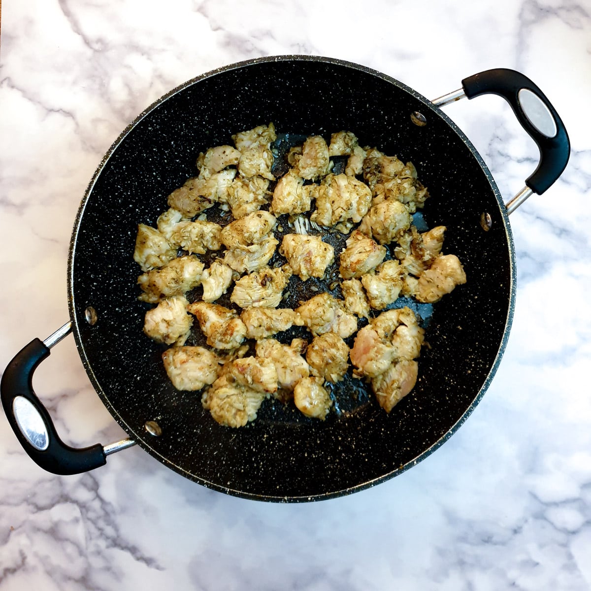Chicken pieces in a frying pan.