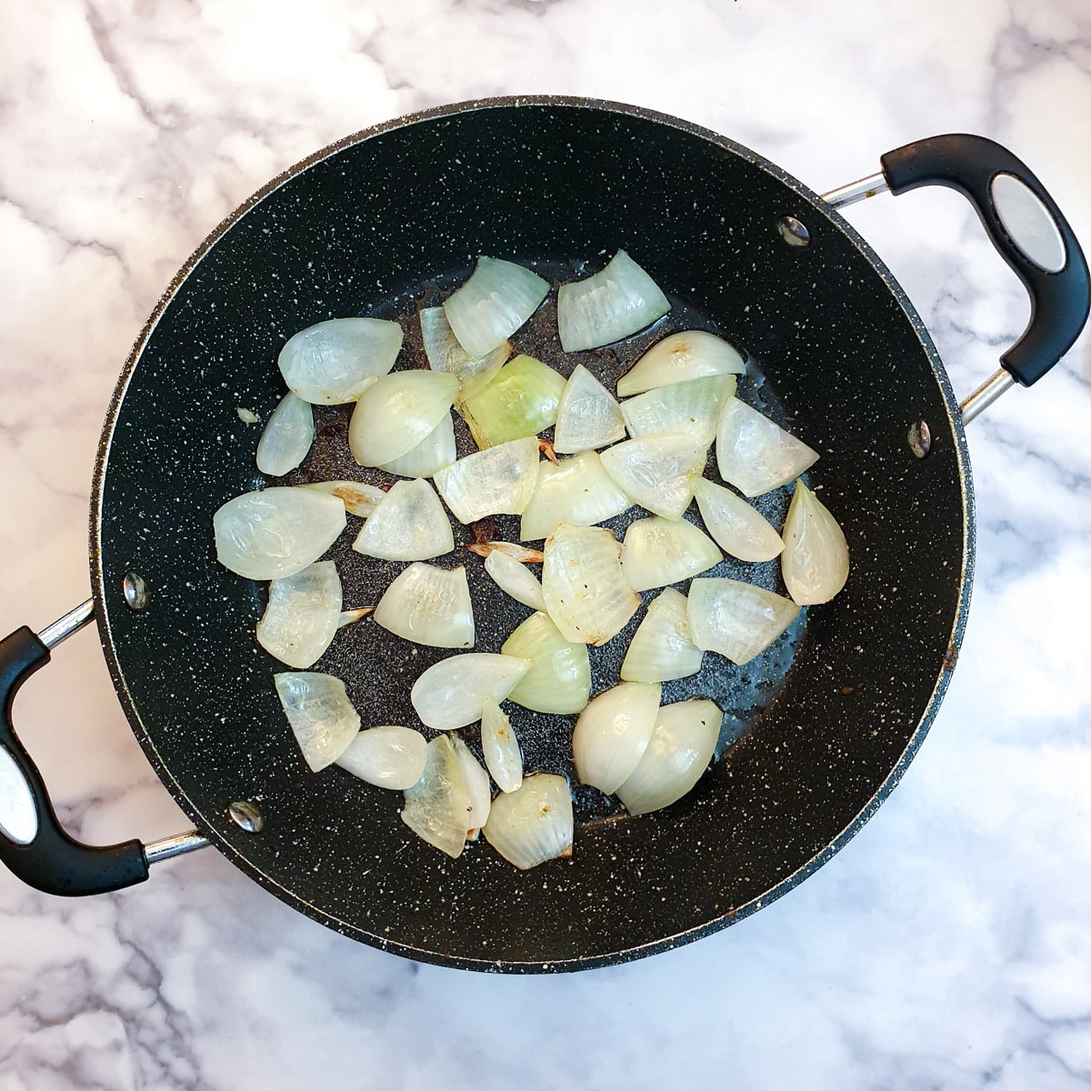 Onions softening in a frying pan.