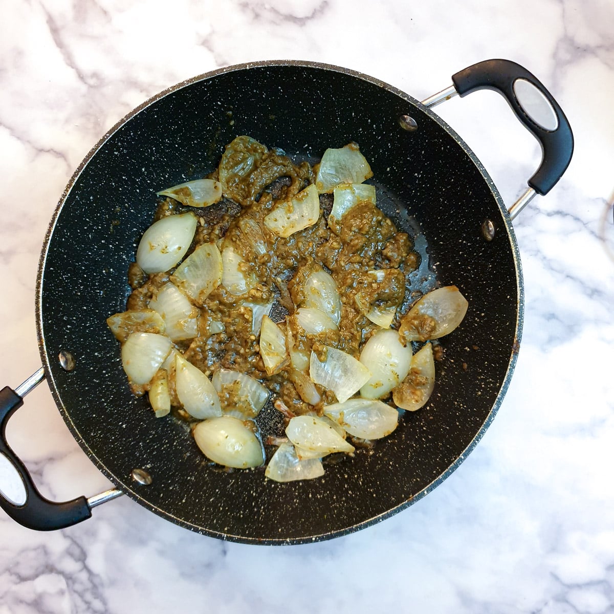Thai sauce and seasonings added to onions in a frying pan.