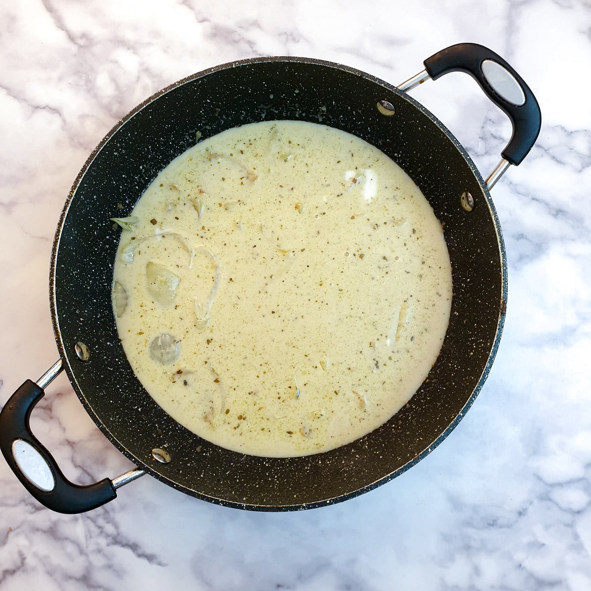 Coconut milk added to onions in a frying pan.