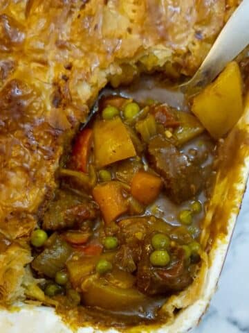 Overhead shot of beef curry pie with a corner cut away to show the filling.