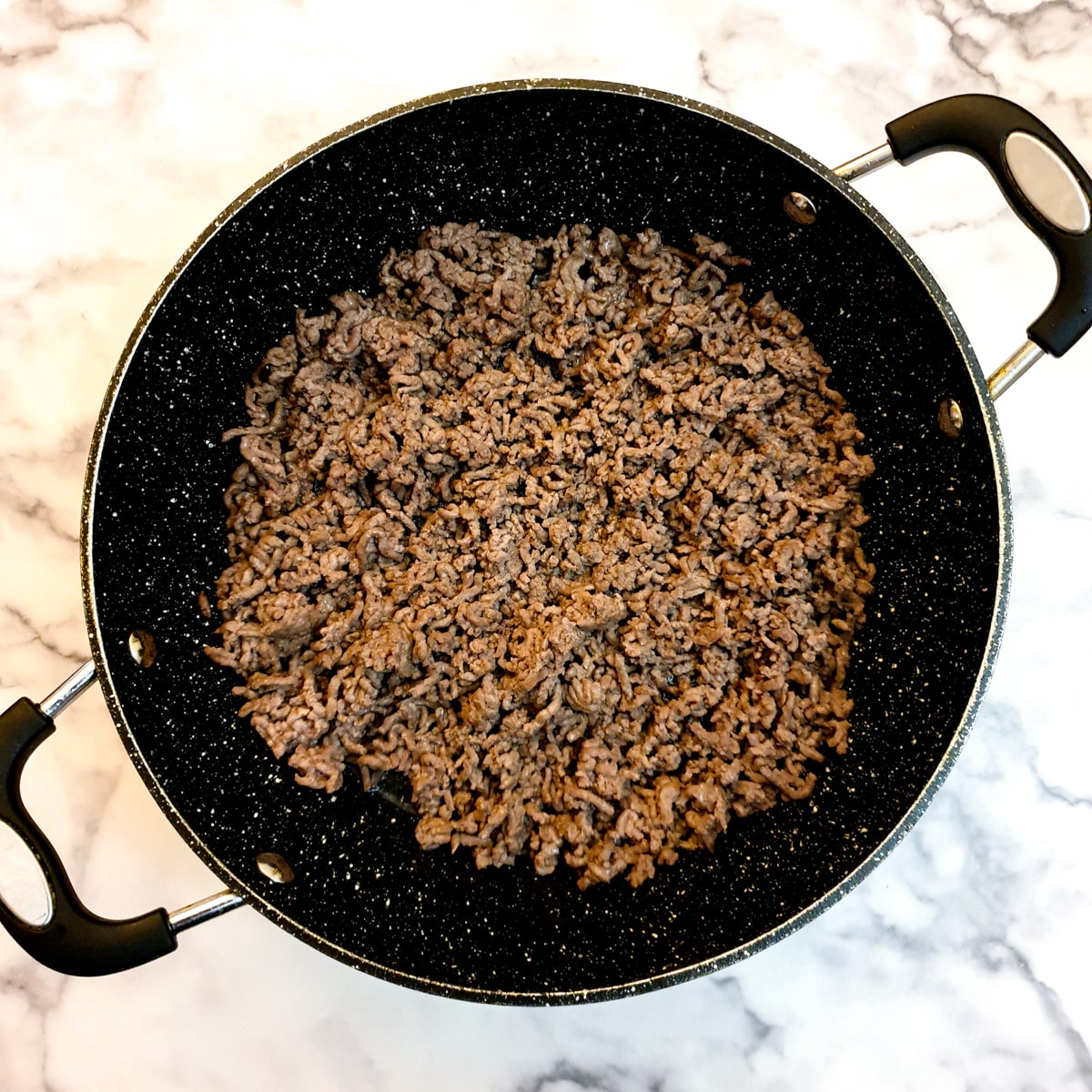 Beef mince being fried in a large frying pan.