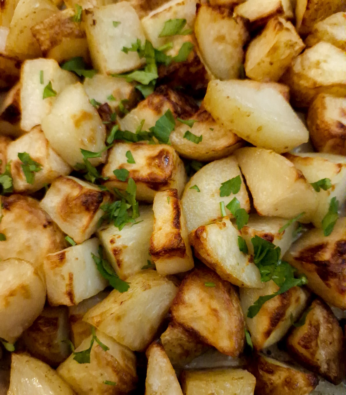 Close up of butter roast potatoes sprinkled with parsley.