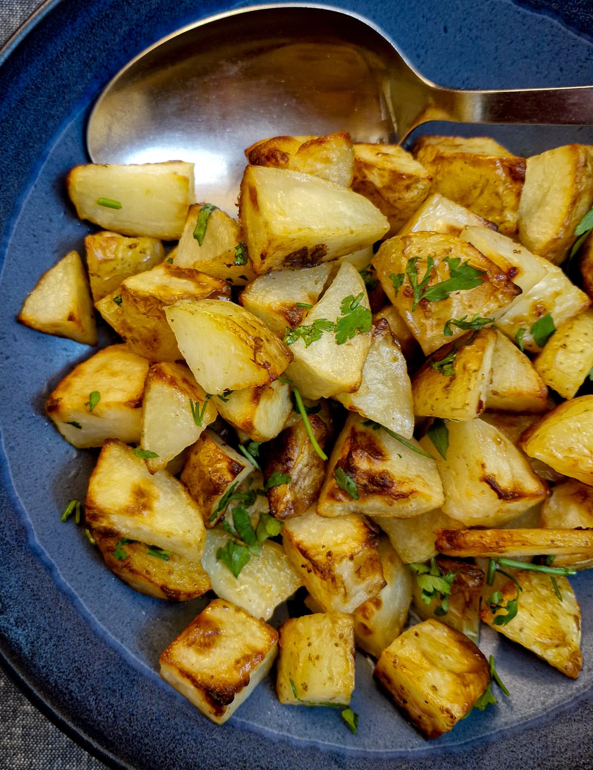 A blue serving dish filled with butter roast potatoes.