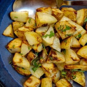 A blue serving dish filled with butter roast potatoes.