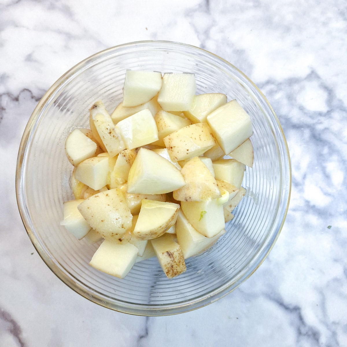 A glass bowl filled with potato cubes.