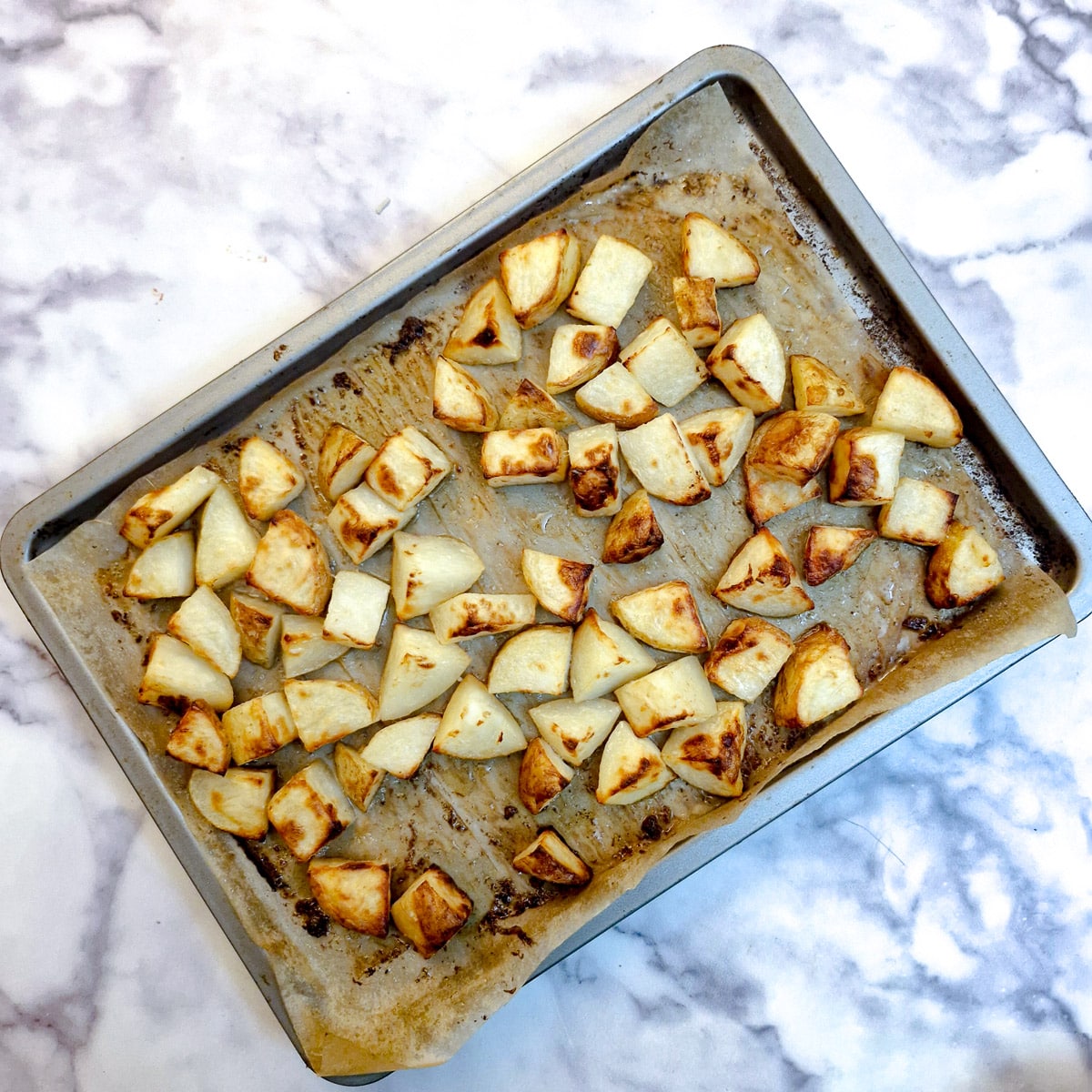 Fully cooked, browned butter roast potatoes on a baking tray.