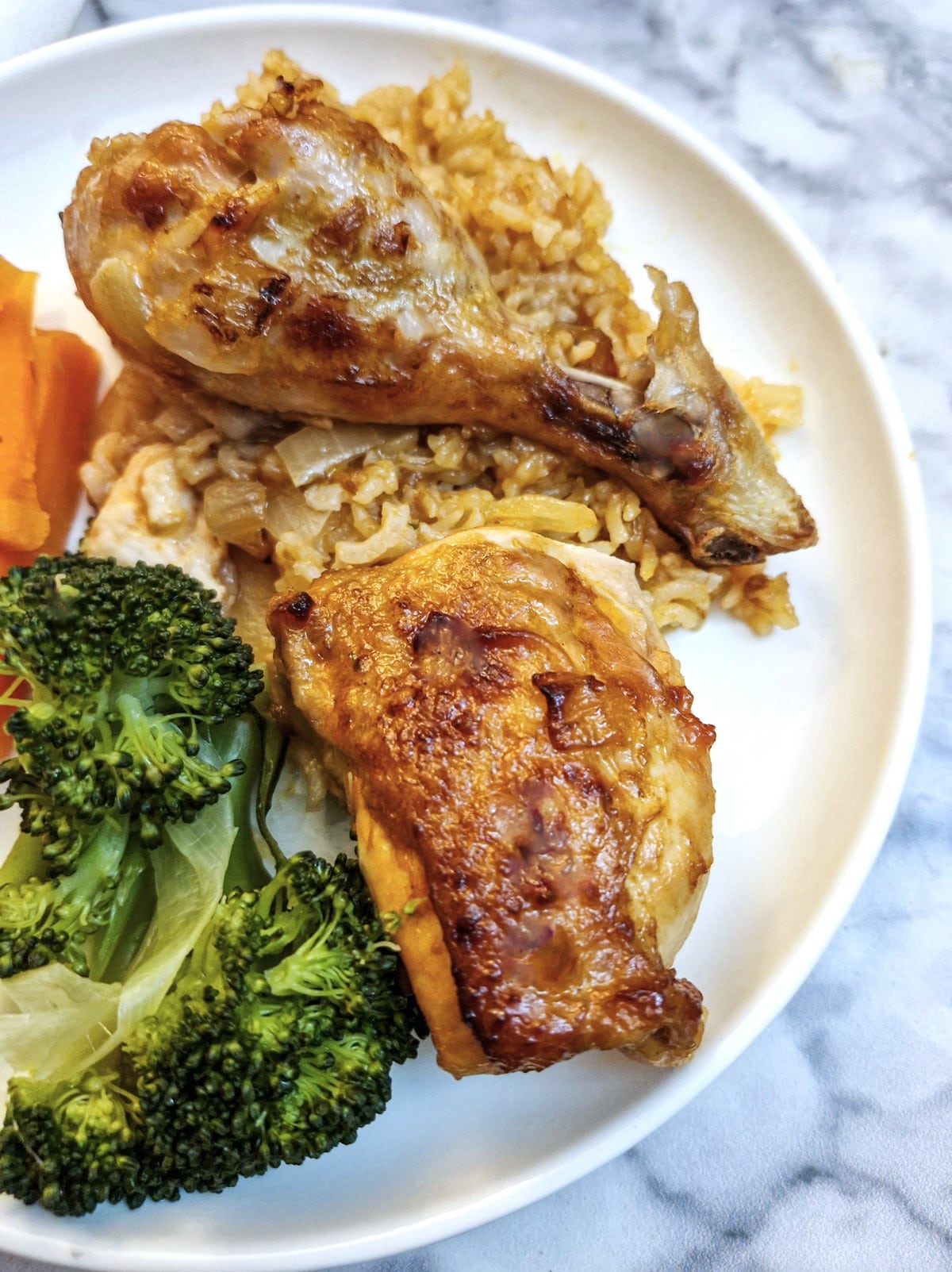 2 pieces of chutney mayonnaise chicken on a bed of onion rice with broccoli and carrots.