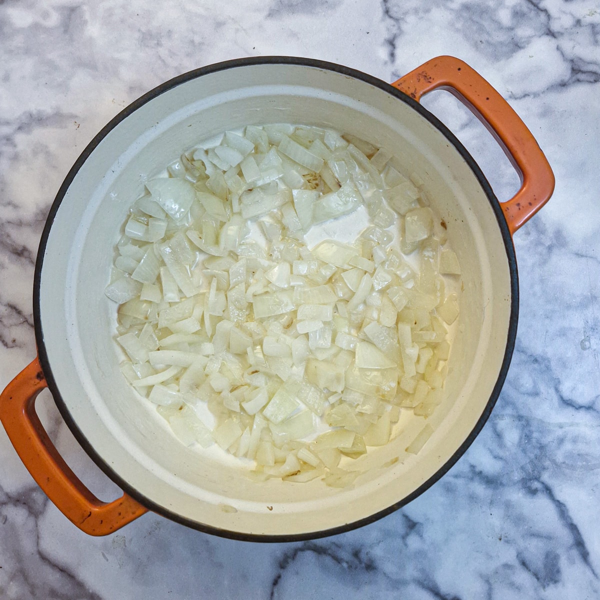 Onions frying in a large casserole dish.