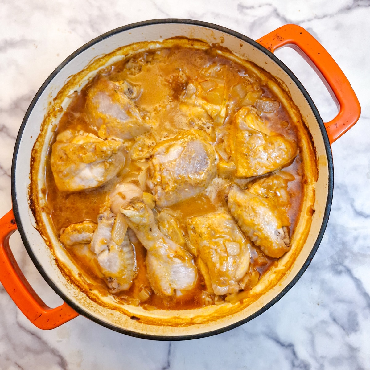 Cooked but still unbrowned chutney chicken in a casserole dish.