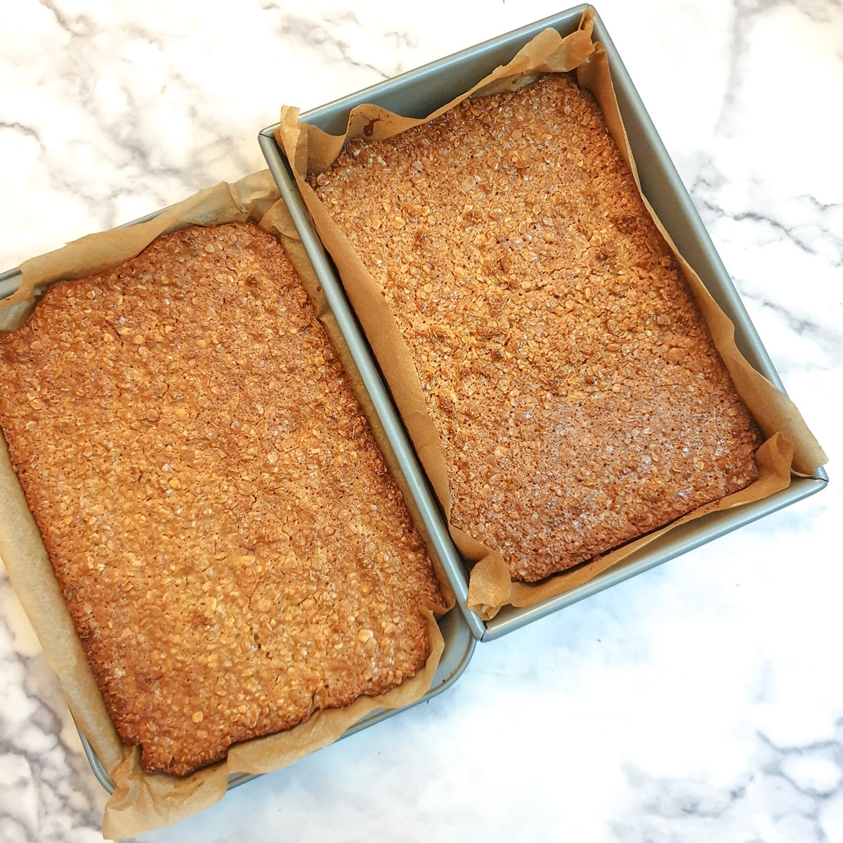 Two trays of baked condensed milk flapjacks.