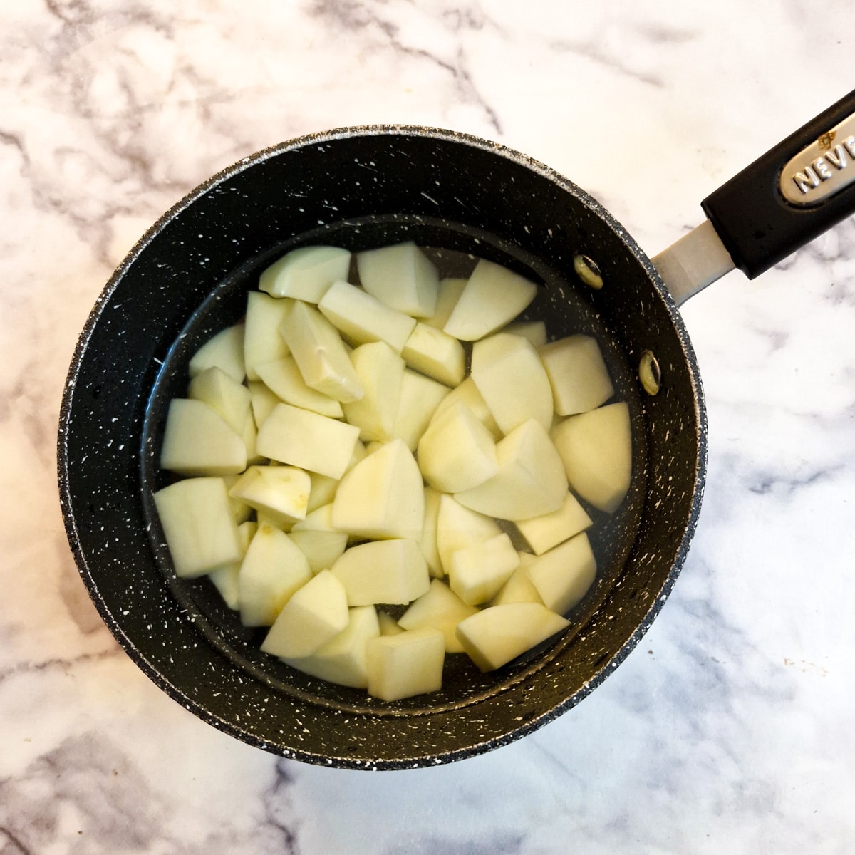 Chopped potatoes in a pan of water.