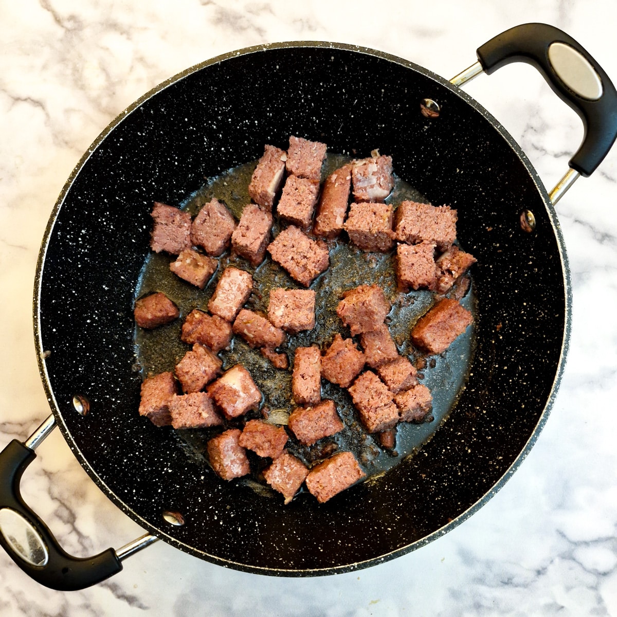 Pieces of corned beef in a frying pan.
