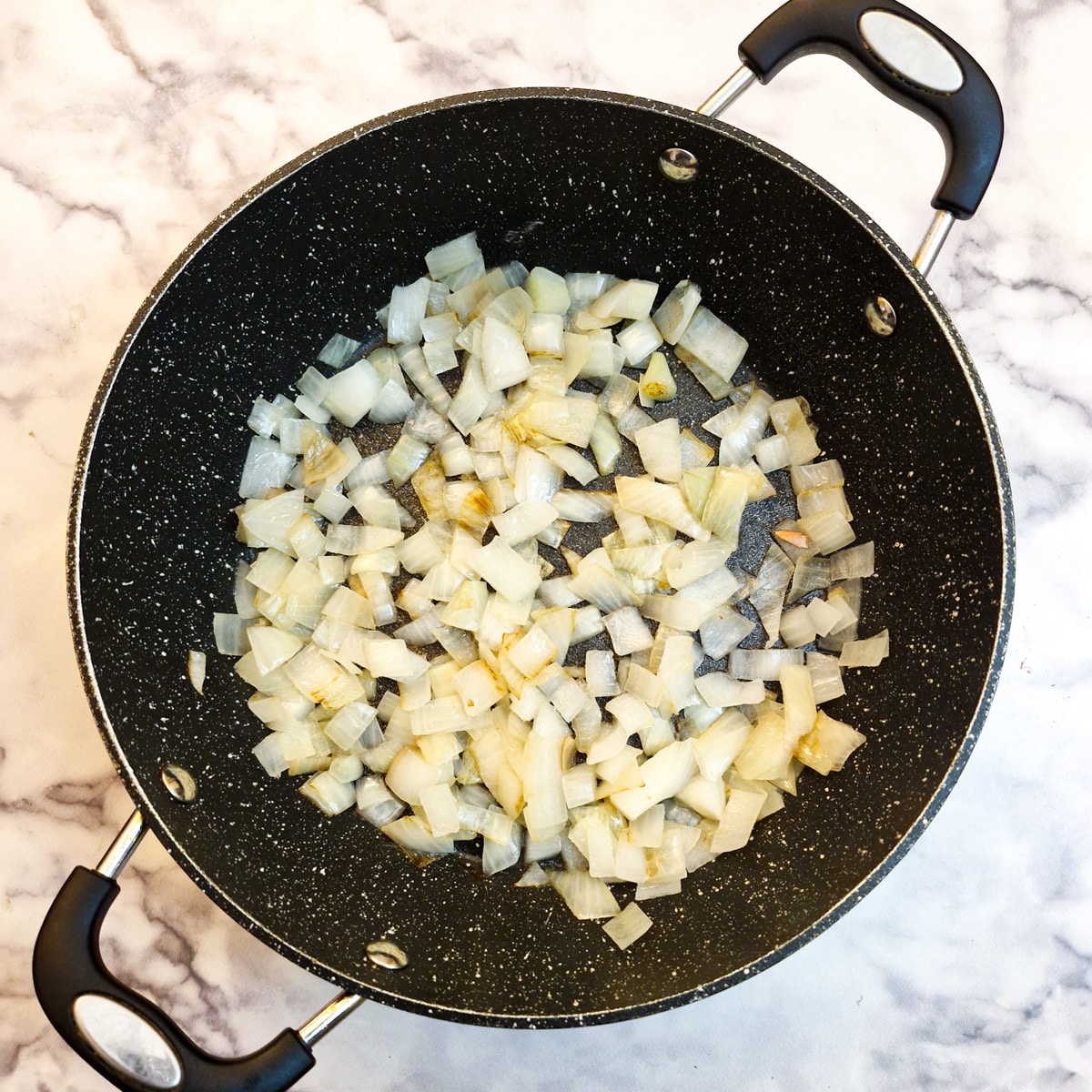 Chopped onions browning in a frying pan.