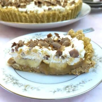 A closeup of a slice of banoffee pie on a plate with the full pie in the background.