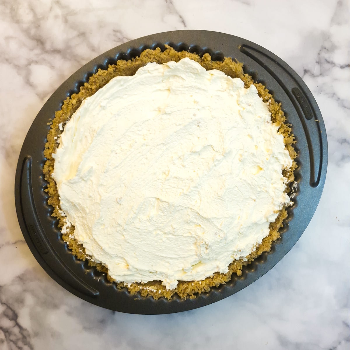 Whipped cream spread on top of a banoffee pie.