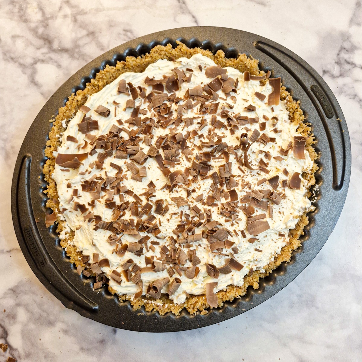 A banoffee pie decorated with chocolate curls.