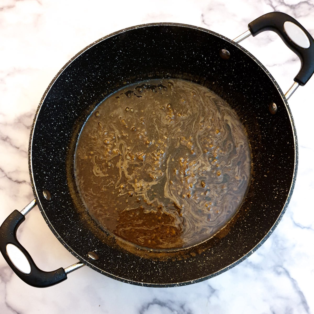 Buttery garlic marsala sauce in a frying pan.