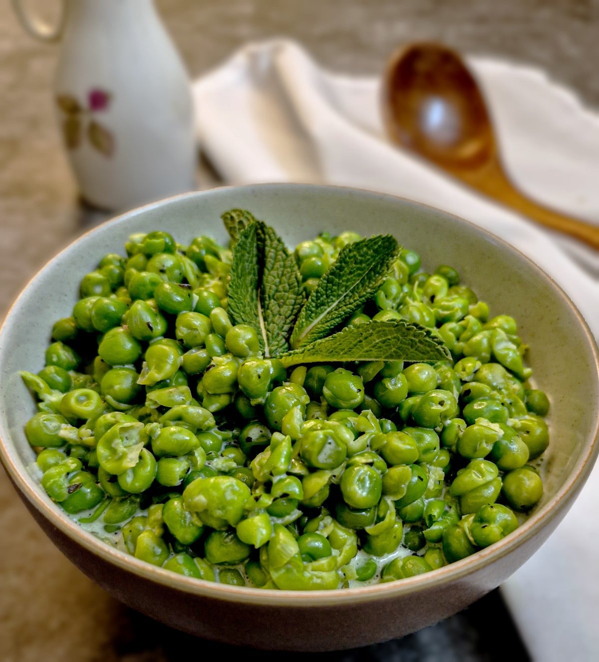 A small dish of minted smashed peas garnished with a mint leaf.