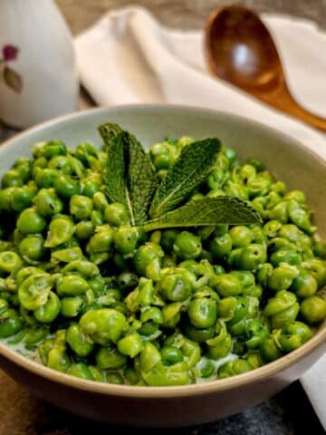 A small dish of minted smashed peas garnished with a mint leaf.