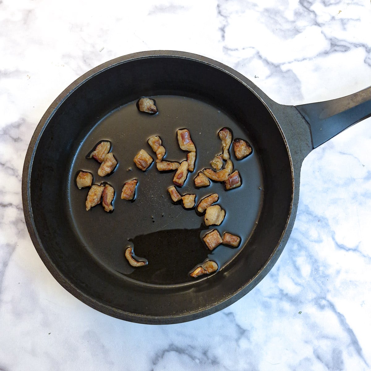 A frying pan holding lamb fat that has been rendered.