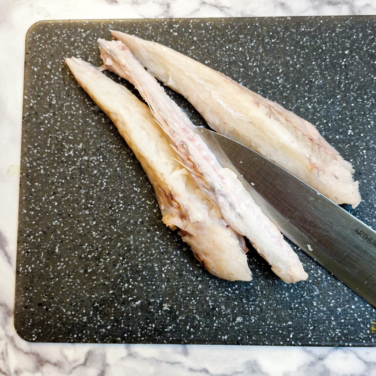 Fillets of monkfish tail being separated from the central bone with a sharp knife.